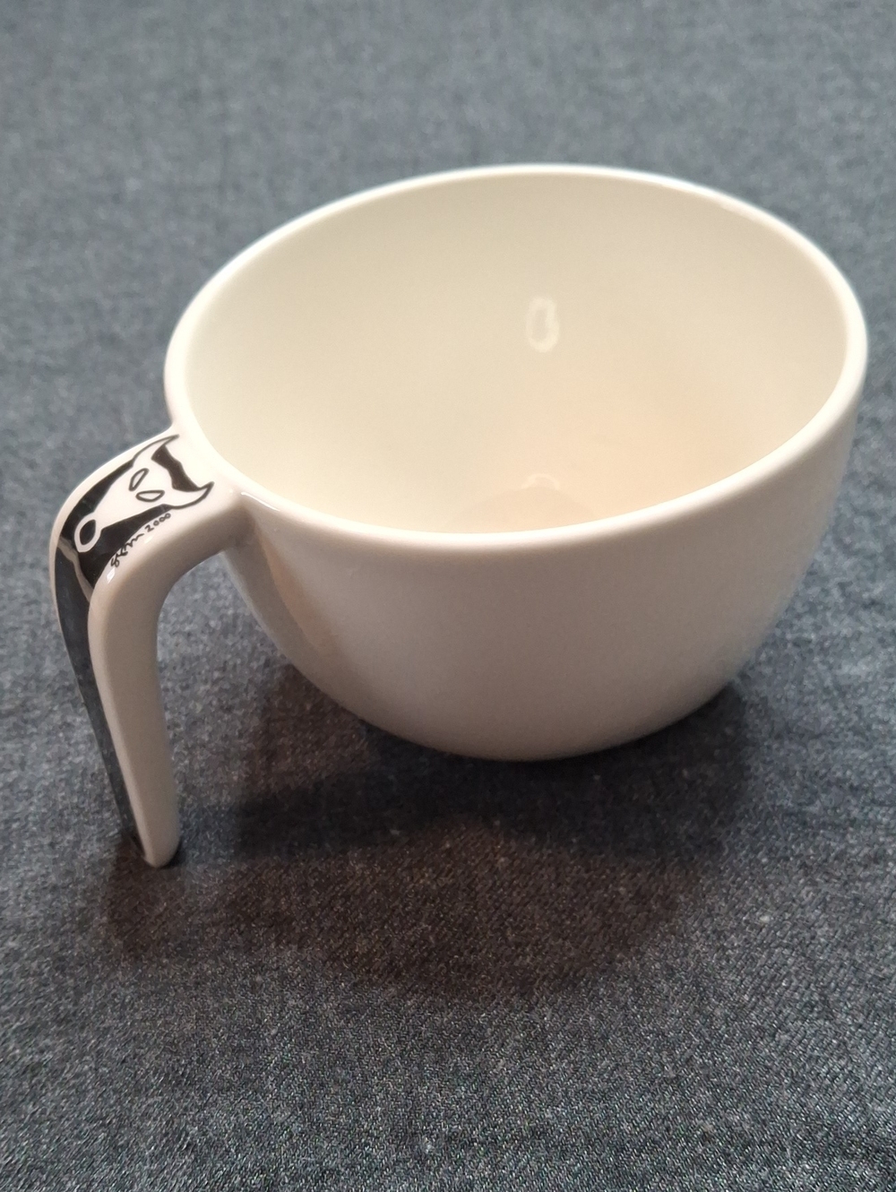 White Ceramic Mug with Black Accent Handle and Playful Graphic